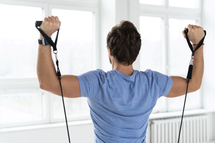 Close-up of the back of a man exercising with resistance bands