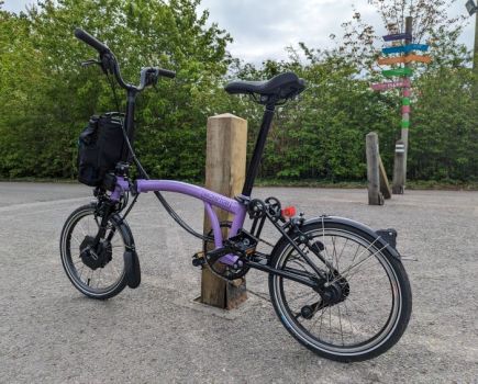 A Brompton bike leaning against a post