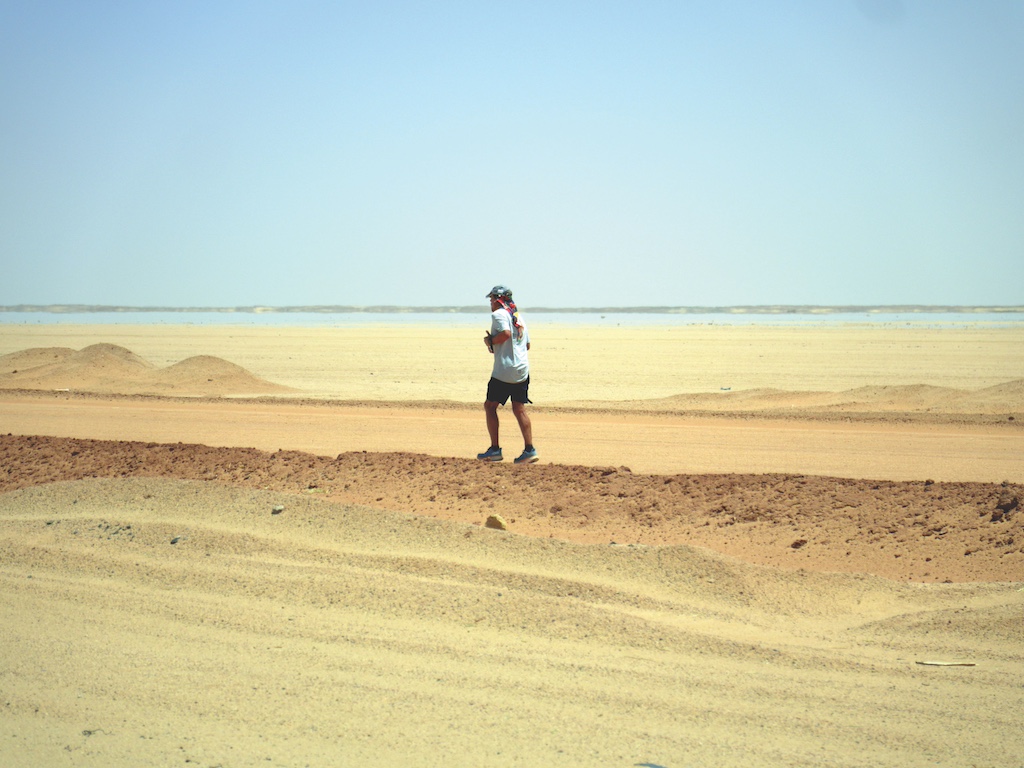 A man runs across sand dunes in Africa