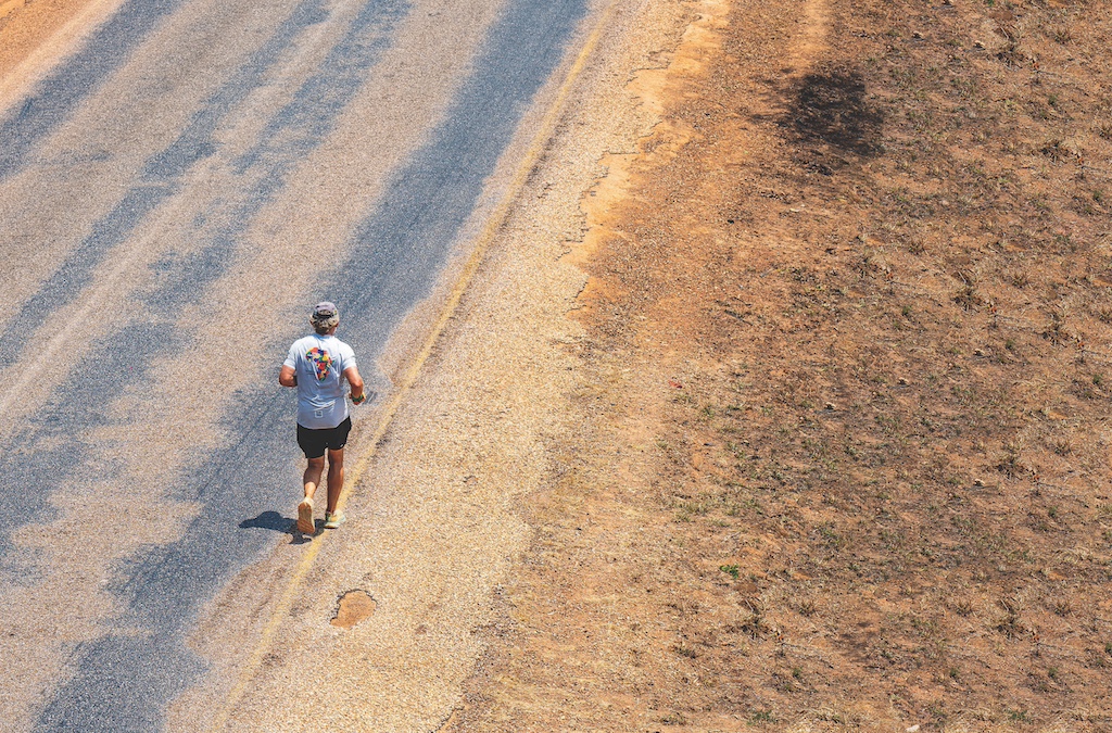 A man runs along a dusty African highway