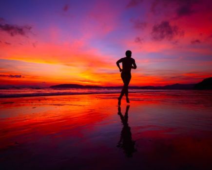 Silhouette of a man running along a beach at sunset
