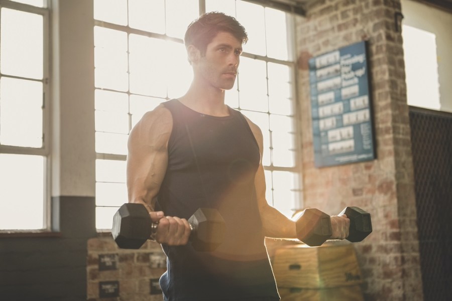 Serious man lifting dumbbells at the gym