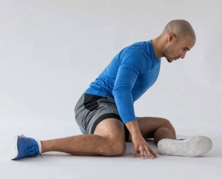 A man performing leg stretches on the floor