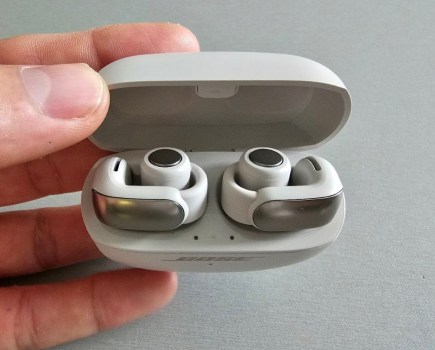 Hand holding a case with open-ear earbuds