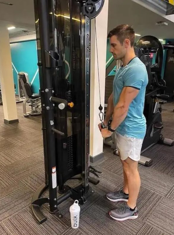 Man in a gym performing a cable triceps push-down