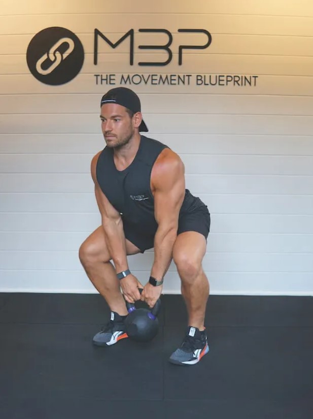 Man performing a kettlebell squat to high pull