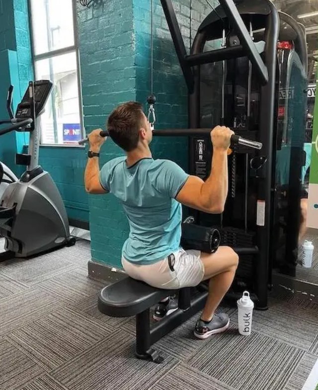 Man in a gym performing a lat pull-down