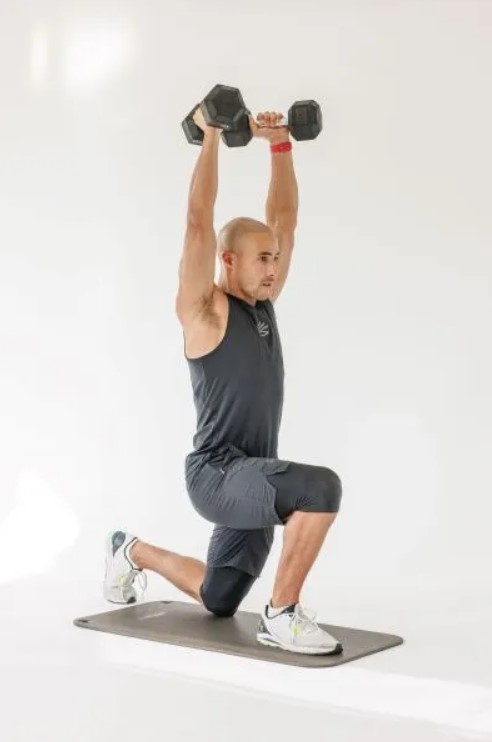 Man performing a reverse lunge dumbbell press