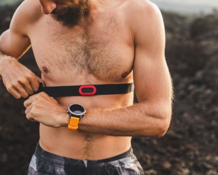 Bare-chested man strapping on a heart rate monitor