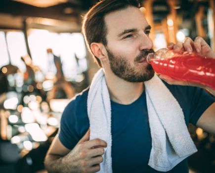 Man in a gym drinking a sports drink