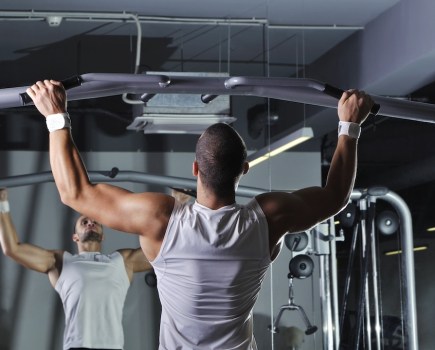 man in gym performing pull-up as part of a functional training plan